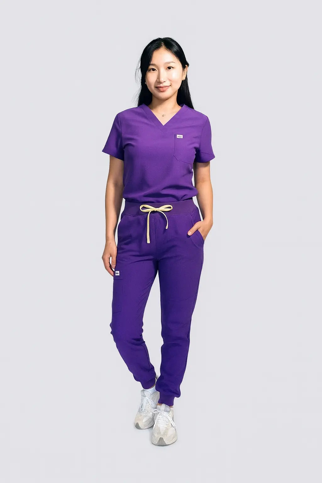 Person wearing a purple scrub set on a light gray background