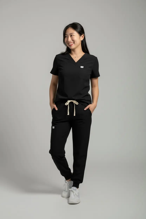 Person wearing a black scrub set with a gray background
